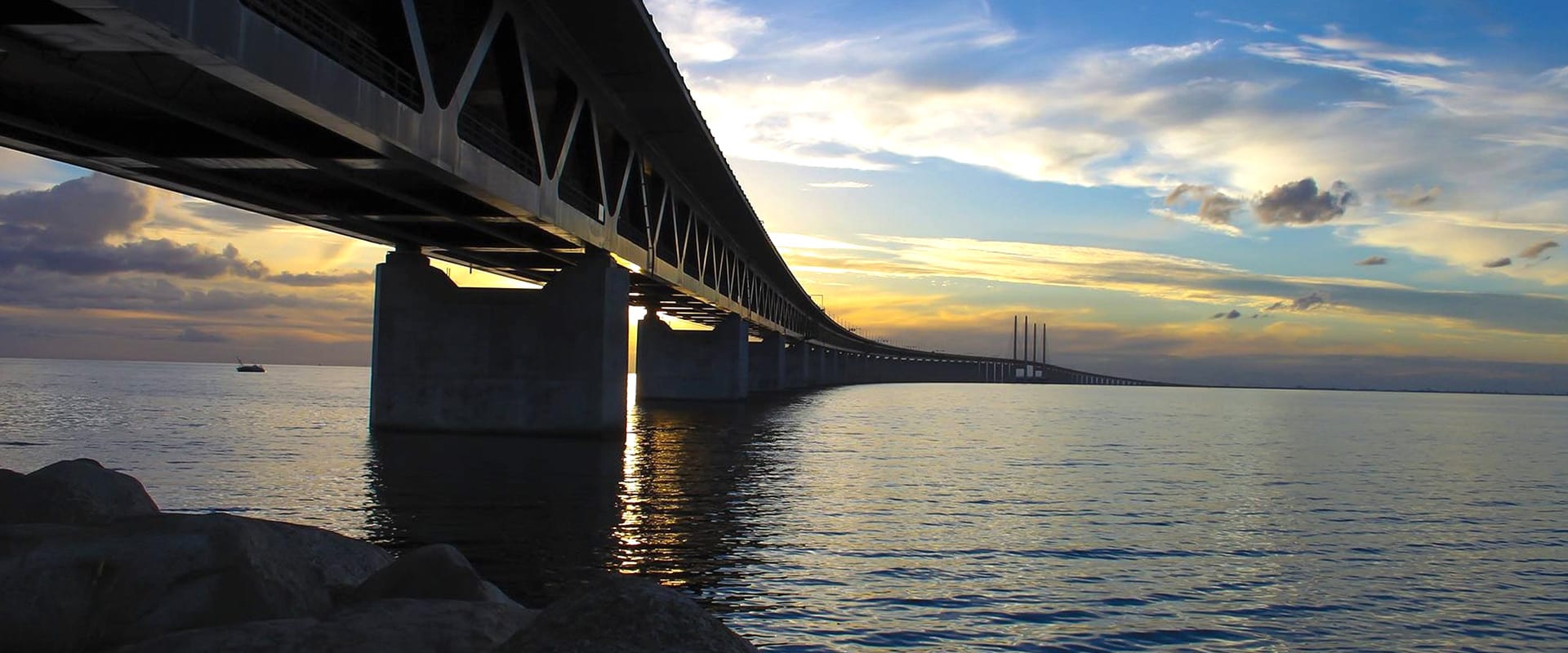Bild på en öresundsbron tagen från stranden i skymningen